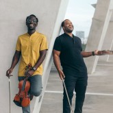 Two males holding violins.