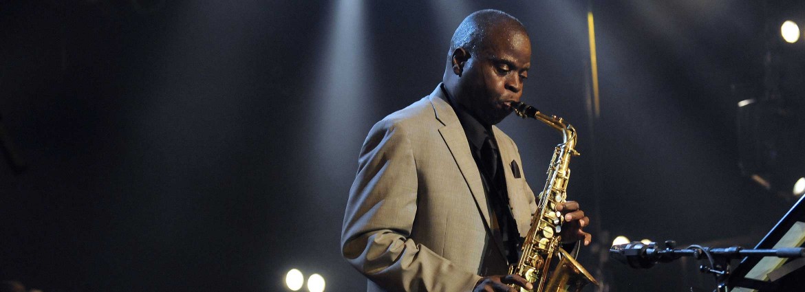 Maceo Parker playing his saxophone on stage.