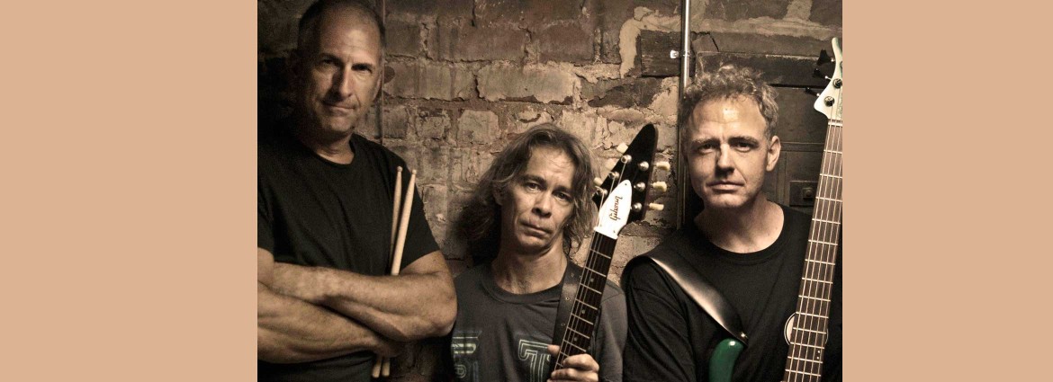 Tim Reynolds & TR3 posing with their guitars and drum sticks.